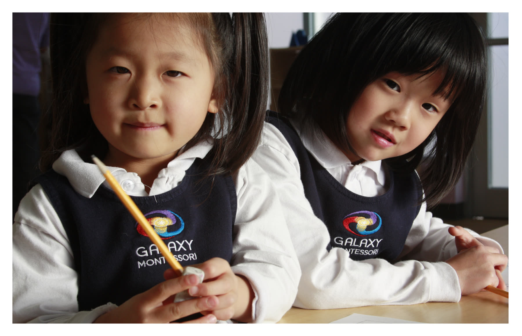 Two Casa students in Galaxy Montessori uniforms at a classroom table